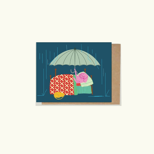 A greeting card featuring an illustration of a pig with an open umbrella and a yellow cat seeking shelter next to the bed, with a blue background and a thermometer in the pigs mouth- feeling under the weather on the inside of the card

