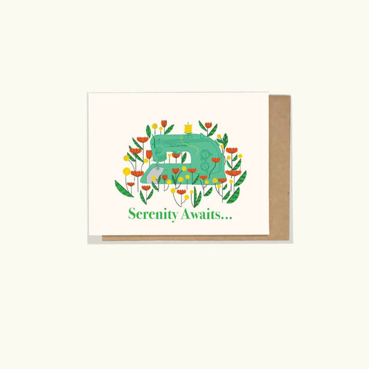 A greeting card with a vintage sewing machine and a floral designs around it and it states 'serenity awaits' on the front