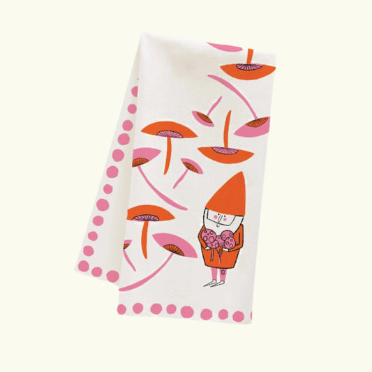 A white dish towel with orange and pink illustrations of gnomes, mushrooms, and polka dots.

