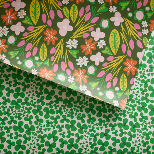Double-sided gift wrap with a floral pattern featuring green and other colors on a background that is partially visible.

