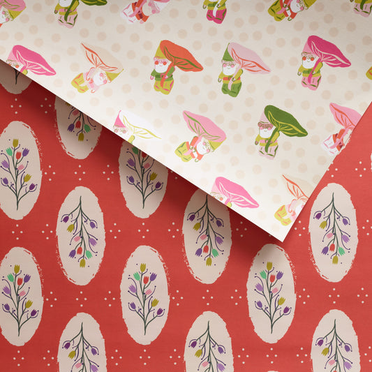 Double-sided wrapping paper with a peeking gnome design on one side and tulip bouquets on the other, set against a muted red background.

