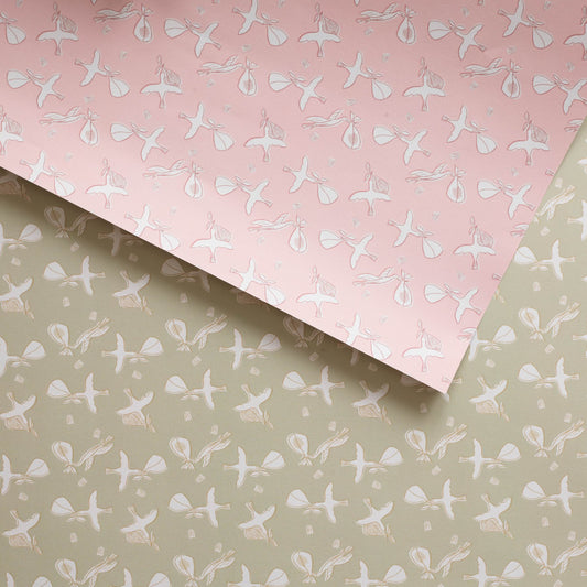 Double sided gift wrap with storks on a pink background on one side and stork on a khaki color on the other